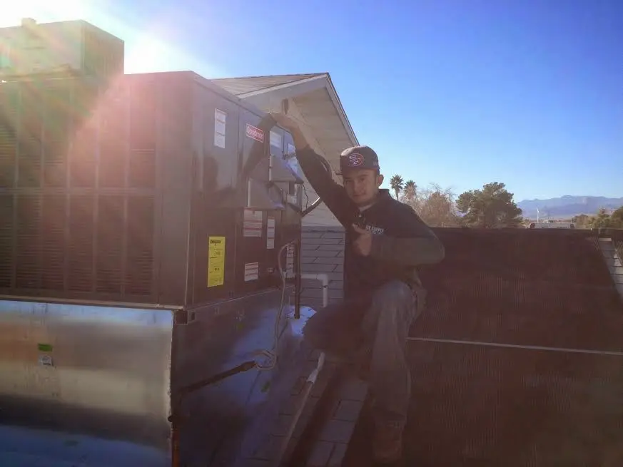 HVAC technician performing AC Tune-Up on a rooftop unit in Rogers